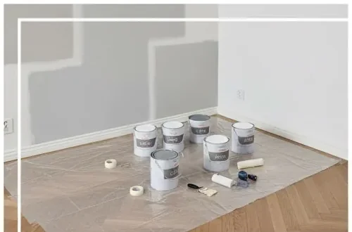 Pots de peinture, rouleau et sol bâché — chantier peinture